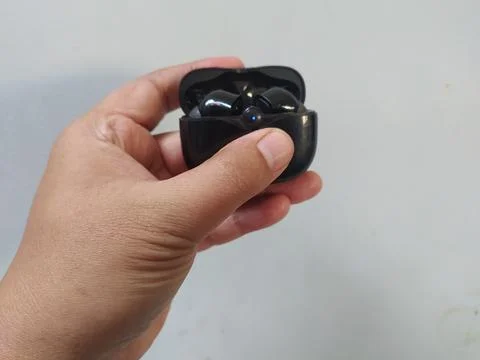 Holding bluetooth headset box black color Stock Photos