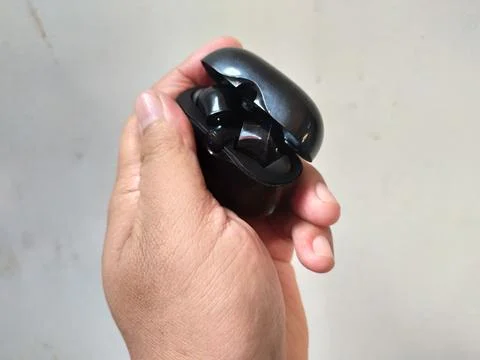 Holding bluetooth headset box black color Stock Photos