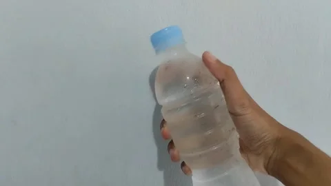 Holding cold water in a plastic bottle on a blue background. Stock Footage 290152404