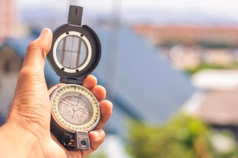 Holding compass on blurred background. Using wallpaper or background travel o Stock Photos