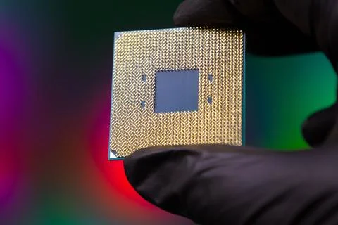 Holding a computer chip with gold pins in a gloved hand in a colorful background Stock Photos