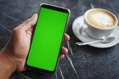 Holding a cpu of coffee and using smart phone with green screen Stock Photos