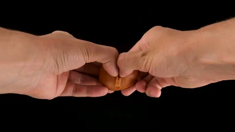 Holding a cracked egg. Breaking an egg. Slow motion. Black background. Stock Footage 144655578