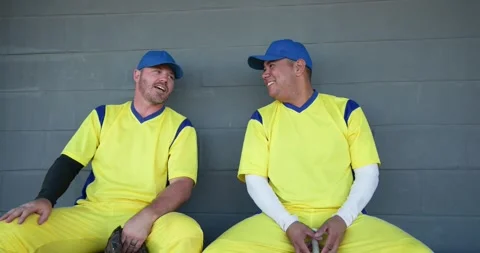 Holding glove and bat, Diverse teammates sparking conversation on dugout bench, Stock Footage 340770993