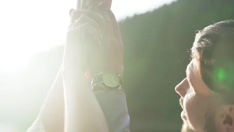 Holding hands against the background of the glare of the sun. Pretty couple Stock Footage 211807626