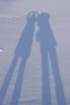 Holding hands creating a shadow in the snow Stock Photos