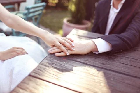 Holding hands with wedding ring in the sunlight Stock Photos