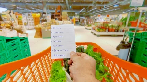 Holding healthy food shopping list at the supermarket grocery cart pov Stock Footage