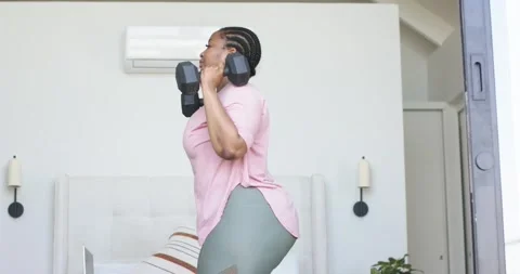 Holding hex dumbbells at shoulder level, woman is stepping into deep lunges for Stock Footage 339558206