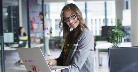 Holding laptop with HTML code overlays, IT professional working in open-plan Stock Photos