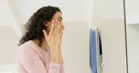 Holding patch and smoothing under right eye, non-binary person treating skin at Stock Footage 337537091