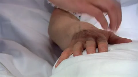 Holding a patients hand in hospital bed Stock Footage