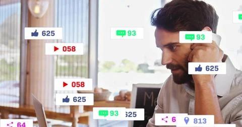 Holding phone, bearded man using laptop at cafe table in button shirt, social Stock Photos