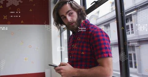 Holding phone bearded man wearing plaid shirt glancing away beside glass window Stock Photos