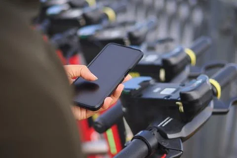 Holding a phone to scan the QR code of the scooters for the ride Фото