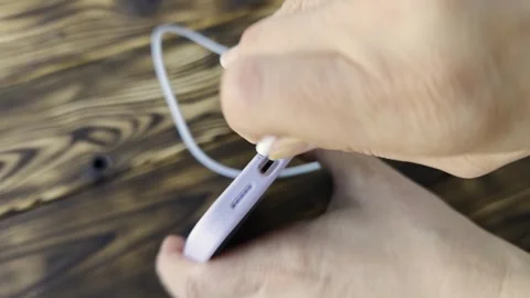 Holding a phone while connecting a charging cable in different frames Stock Footage 340461854