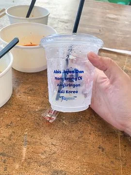 Holding a refreshing iced drink in a clear plastic cup inside a warm cozy l.. Stock Photos