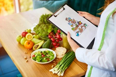 Holding schematic meal plan for diet with healthy products on background Foto stock