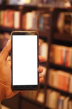 Holding smart phone with empty screen against library background Stock Photos