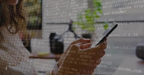 Holding smartphone, female coder scanning ports at desk with monitor and coffee Stock-Fotos
