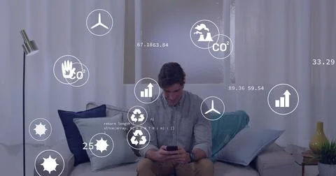 Holding smartphone, man analyzing data overlays on sofa with pillows, lamp, Stock Photos
