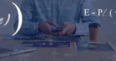 Holding smartphone over tablet, man wearing light blue shirt analyzing charts at Stock Photos