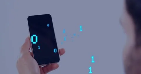 Holding smartphone showing cyan binary digits in studio, blurred face in dark Foto stock