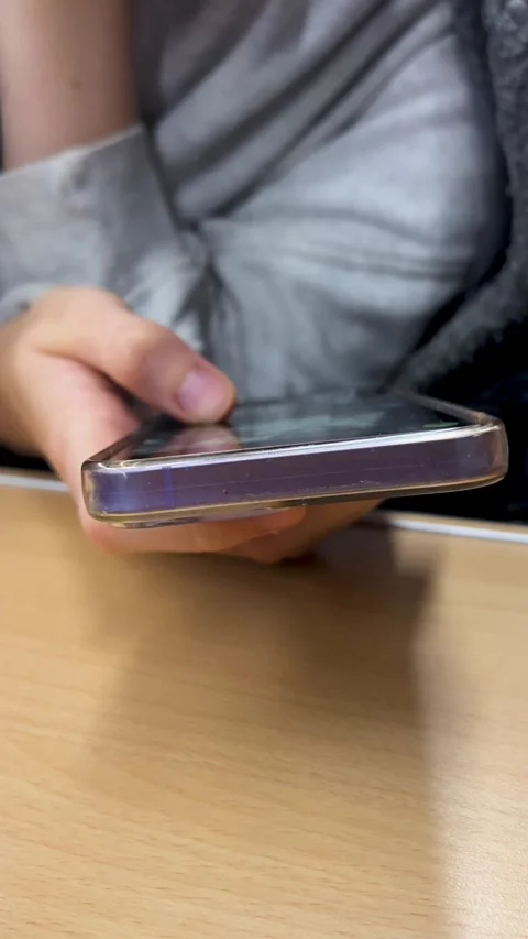 Holding a Smartphone While Sitting at a Table in a Casual Indoor Setting Stock Footage 296106425