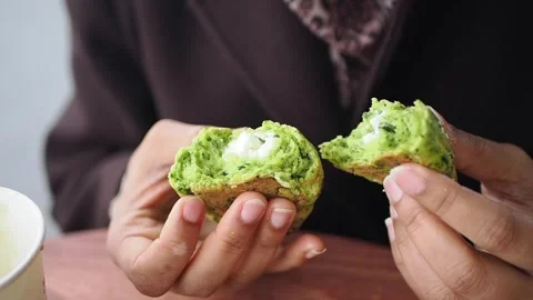 Holding a split green-colored baked snack, such as a spinach or matcha muffin Stock Footage 341733510