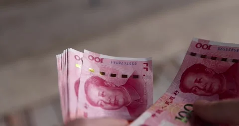 Holding a stack of red Chinese yuan in his hand on a background, holding a large Stock Footage 314091679