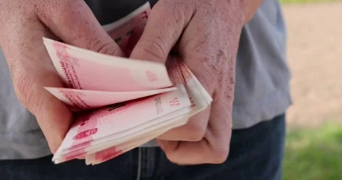 Holding a stack of red yuan in hand, holding a large amount of money in yuan in Stock Footage 314351486