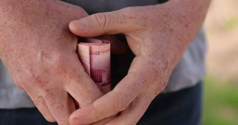 Holding a stack of red yuan in his hand on a background, holding a large amount Stock Footage 314151136