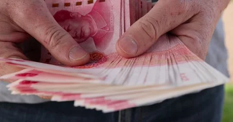 Holding a stack of yuan in his hand on a background, holding a large amount of Stock Footage 318208259