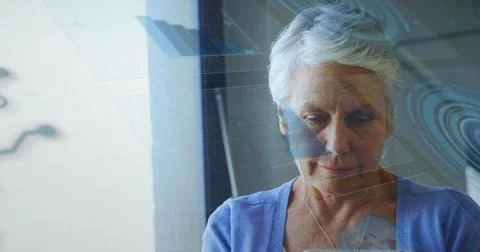 Holding tablet and scanning digital overlays near window, woman in cardigan and Stock Photos