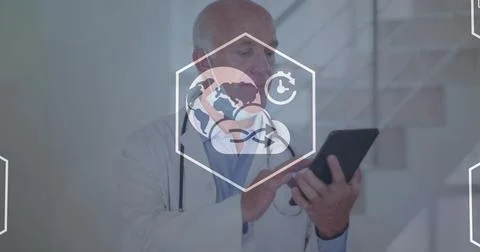 Holding tablet, senior doc using screen in clinic wearing coat and stethoscope Stockfoto's