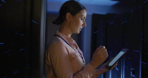 Holding tablet, tech inspecting LED-lit racks at data center, wearing pink sh Foto stock