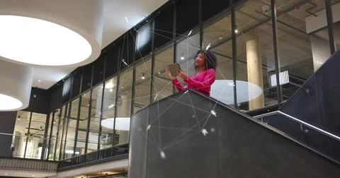 Holding tablet while wearing pink blazer and standing on balcony in corporate Stock Photos