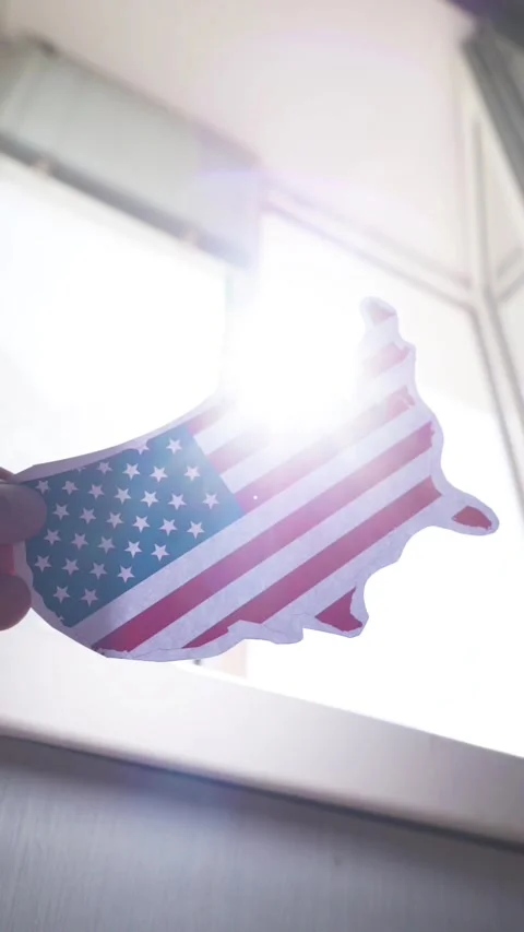 Holding US map with flag pattern against window with bright sun flares, concept 스톡 동영상 343956557