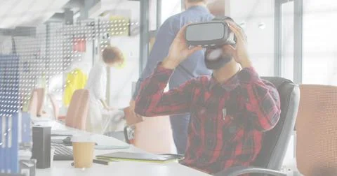 Holding VR headset, man in red plaid shirt testing virtual app at open-plan Stock Photos