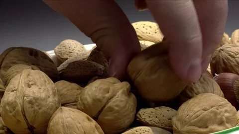 Holding Walnut in Shell with Other Mixed Nuts Isolated on Black, 4K Stock Footage 70124022