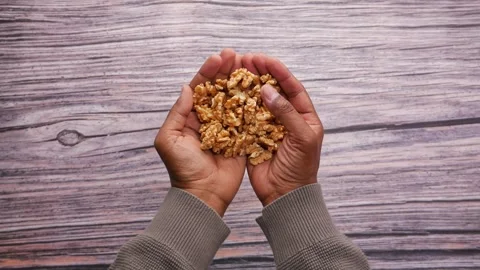 Holding walnuts in hands over wooden surface Stock Footage 342780663