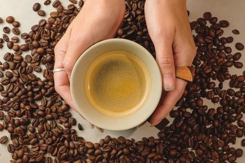 Holding a warm cup of coffee surrounded by aromatic coffee beans Stock Photos