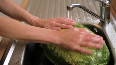 Holding watermelon under cold stream Stock Footage 328372220