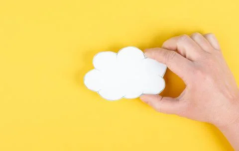 Holding a white cloud in the hand, empty copy space for text, yellow background, Stock Photos