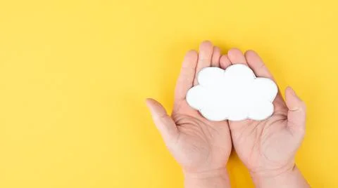 Holding a white cloud in the hand, empty copy space for text, yellow background, Stock Photos