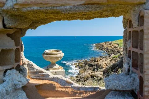 A hole in a brick-wall reveals a beautiful mediterranean scenery Stock Photos