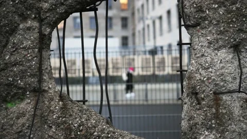 Hole in Broken Berlin wall and walking person against Vídeos de archivo 230175797