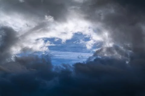 A hole in the dark clouds show a portion of blue sky Stock Photos