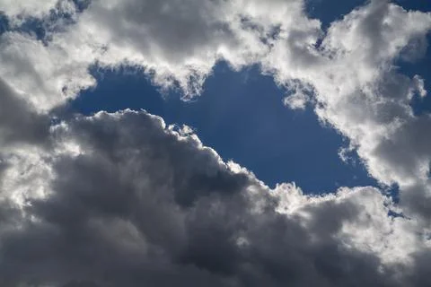 A hole in the dark clouds show a portion of blue sky Stock Photos