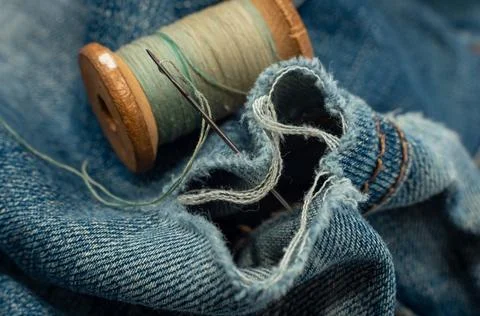 Hole in jeans. Needle with thread for darning jeans. Tools for work dressmake 写真素材